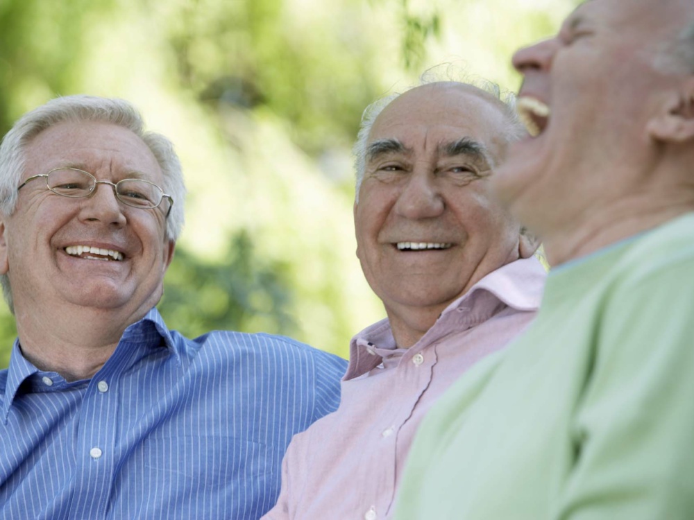 Three senior men laughing, close-up (focus on man wearing glasses)