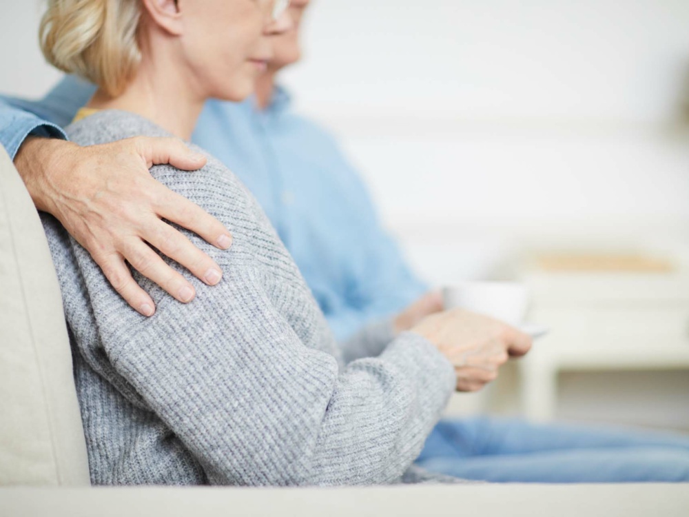 Hand of senior husband on shoulder of his wife during family idyl at home