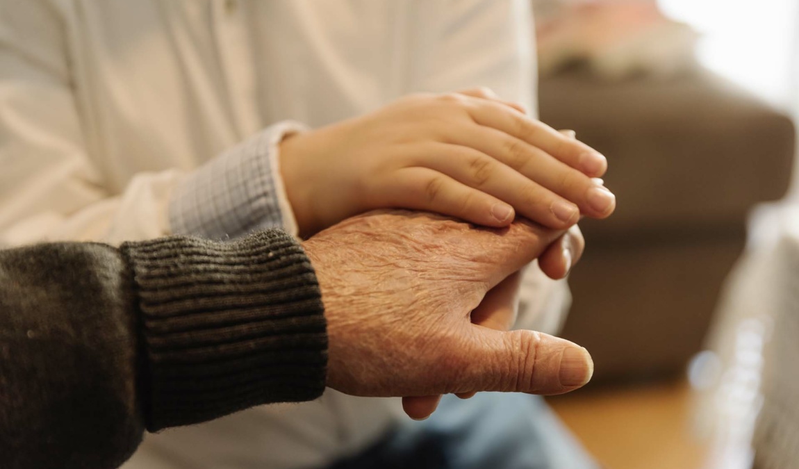 Hand of old person holding hand of kid. Old Age Concept.